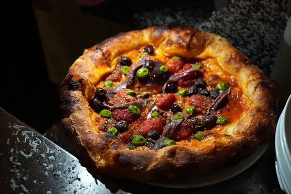 Anchovy and olive pizza with herb sauce and tomato, The Food Hub pizza catering