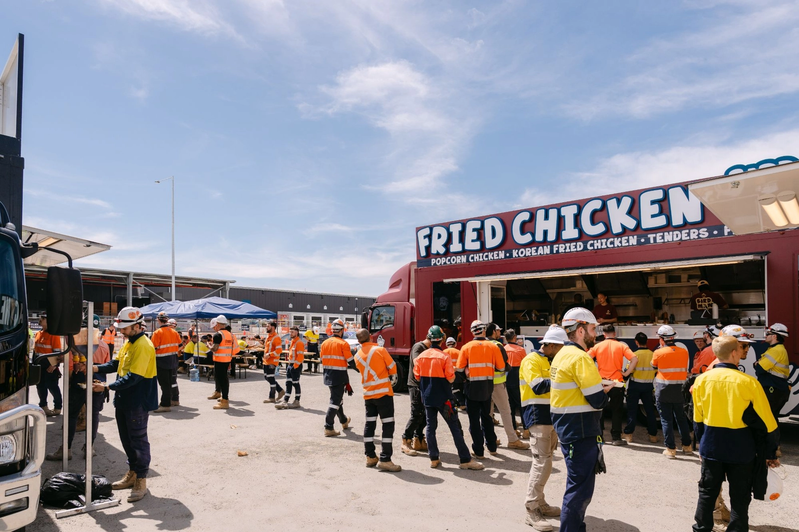Construction workers in hi vis lining up at the Birdman fried chicken truck for a site lunch in Moorebank
