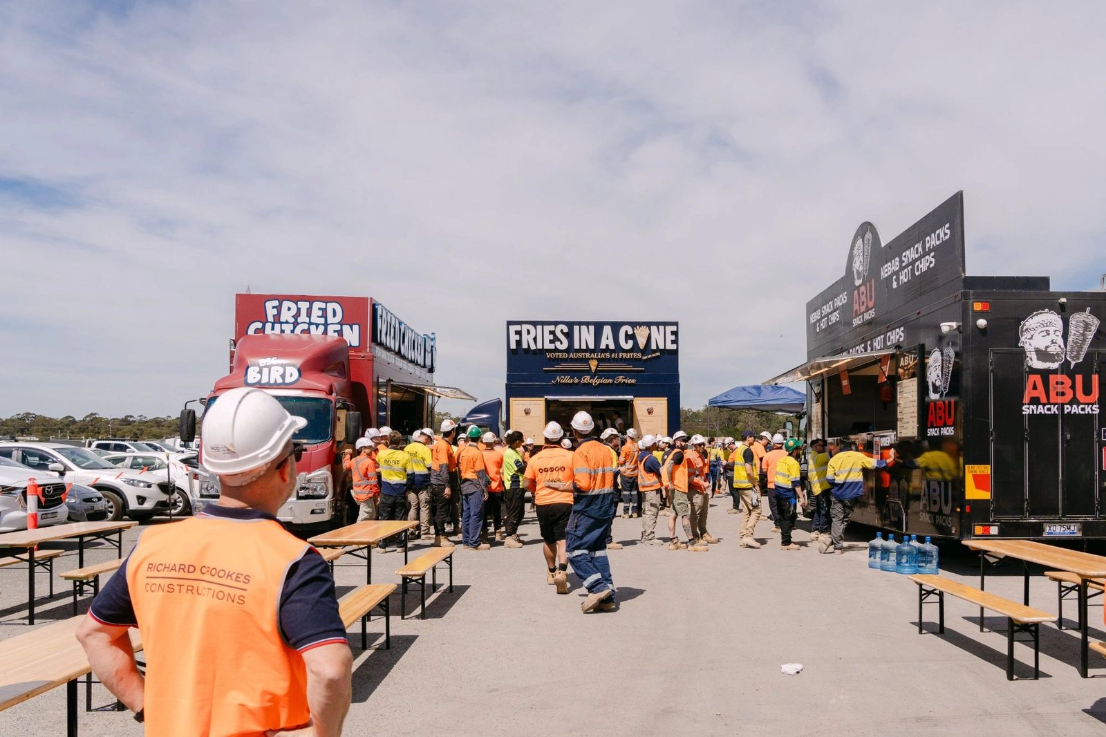 Three Food Hub trucks serving a construction crew in hi vis on a building site in Moorebank, Sydney